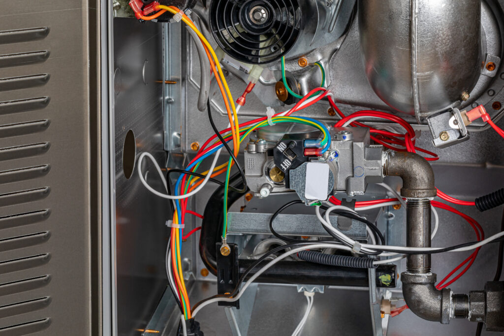 The inside of a gas furnace with valves and wires visible